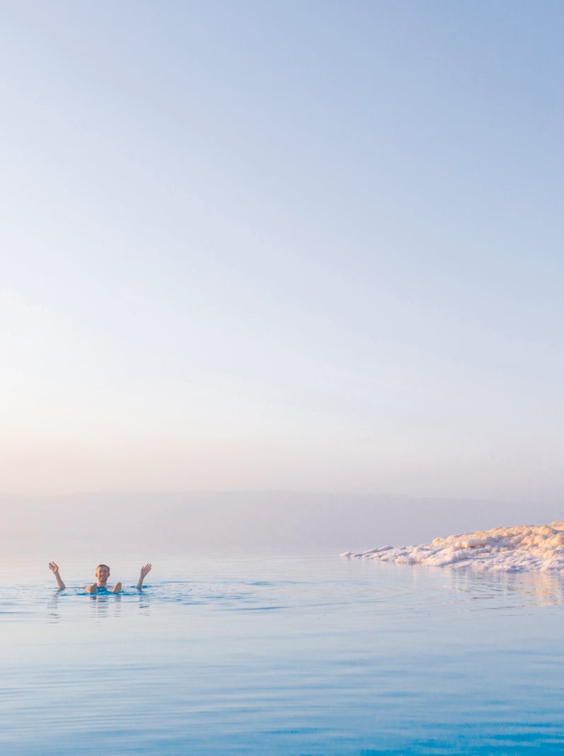 Tourist swims in turquoise water of the Dead Sea. Jordan landscape