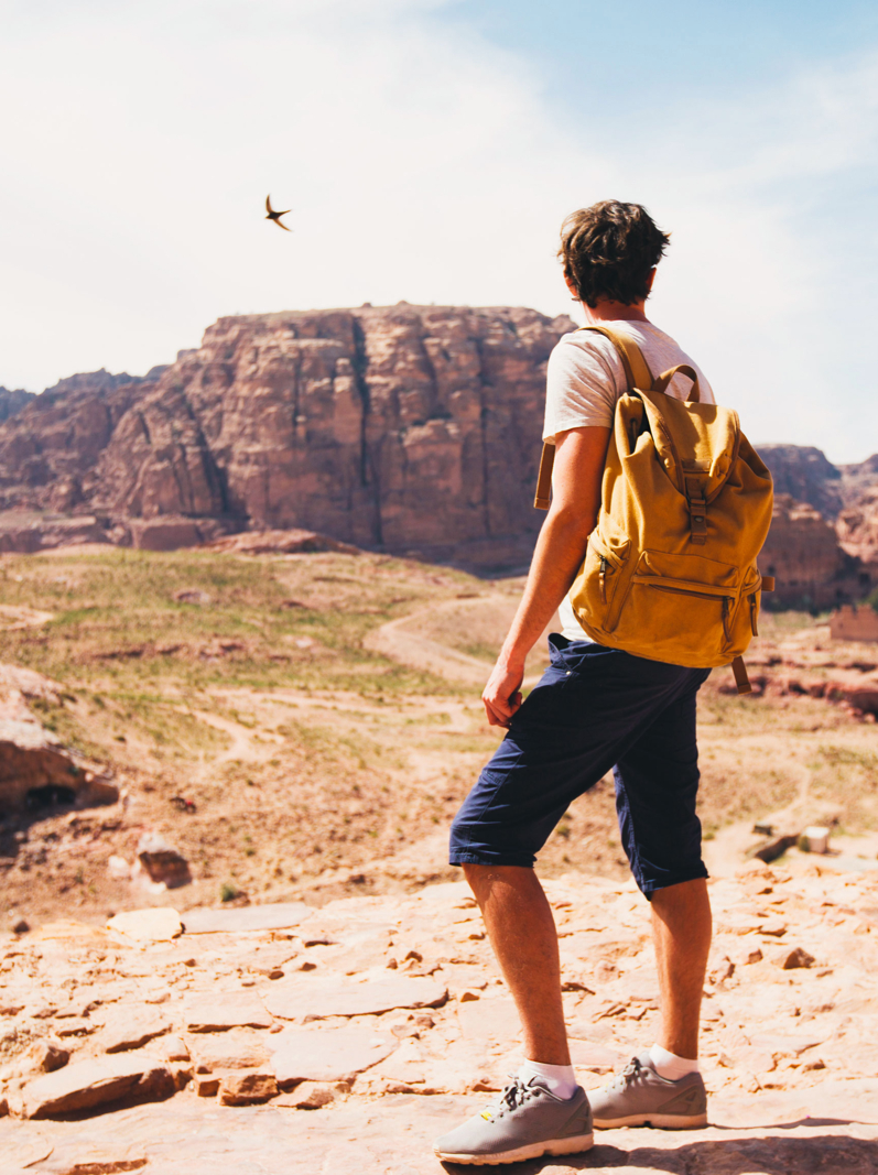 Homme de randonnée avec sac à dos jouissant de la vue sur la vallée depuis le sommet d'une montagne. Les montagnes de la Jordanie. Concept de voyage et d'aventure