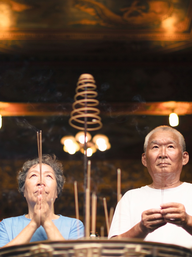 couple âgé priant la bouddha avec une bâton d'encens au temple