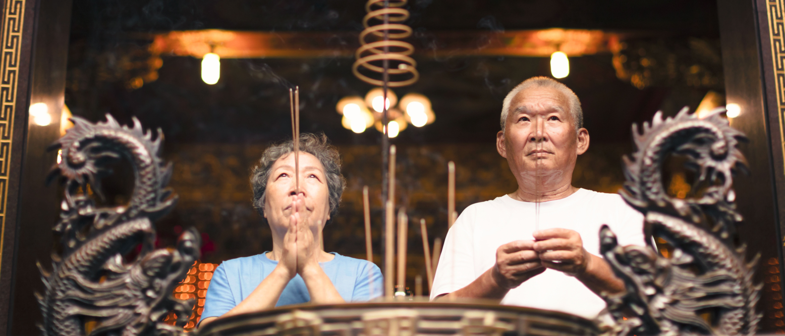 couple âgé priant la bouddha avec une bâton d'encens au temple