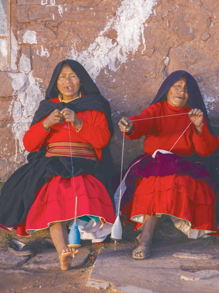 A photo of four women sitting together spinning wool on Taquile Island, Lake Titicaca, Peru