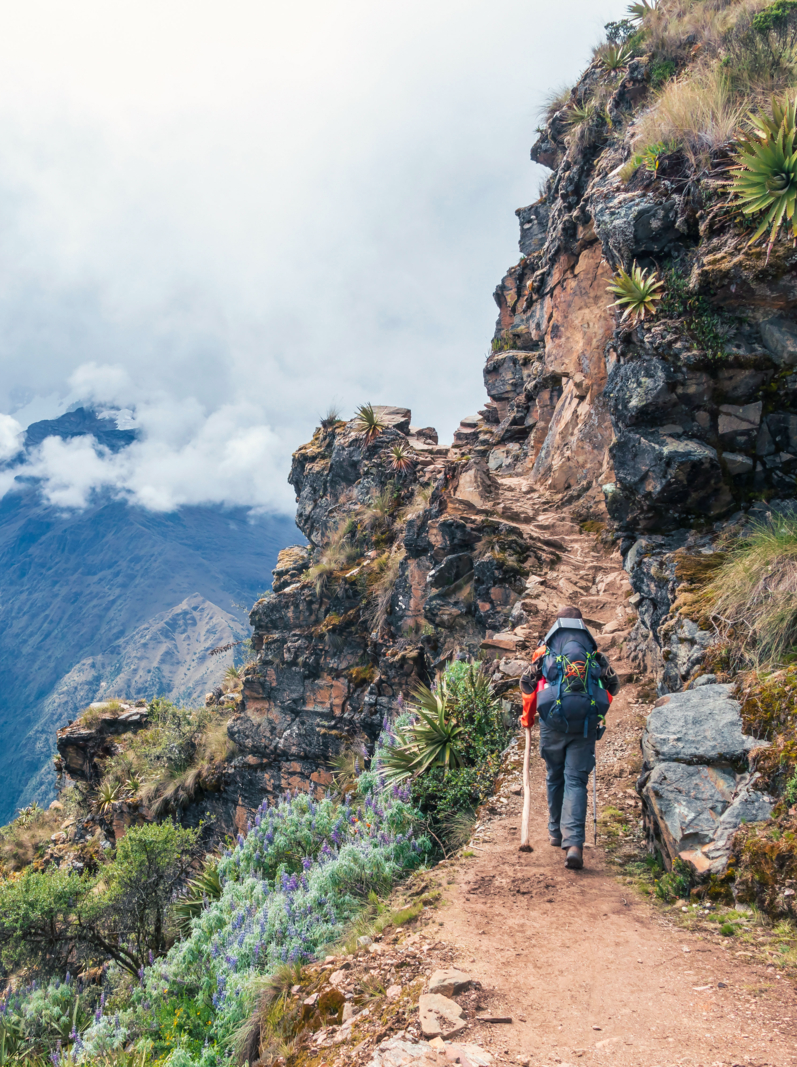 Young hiker man trekking with backpack in Peruvian mountains. Active outdoor vocation getaway hiking in Peru