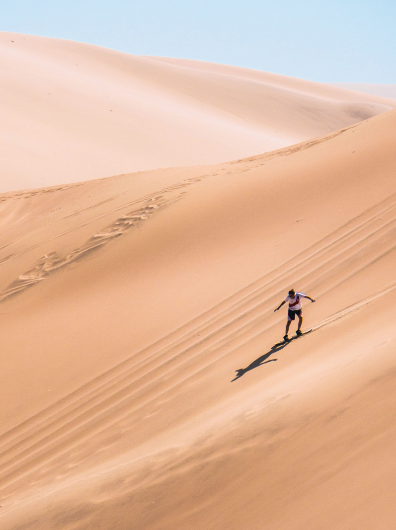 silhouette d'homme pratiquant le sandboard dans le désert du Pérou.