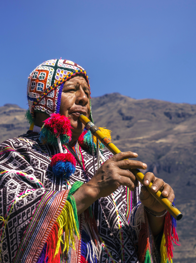 Senior man dressing traditional peruvian clothing and playing flute