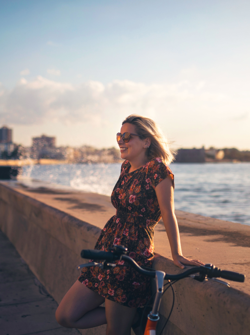 Woman with bicycle enjoying sunset in the city