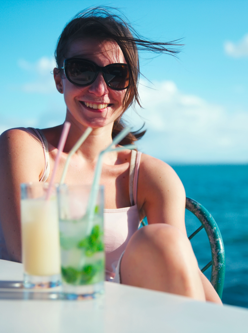 Skinny girl in sunglasses drink mojitos and pina colada on a background of the Caribbean