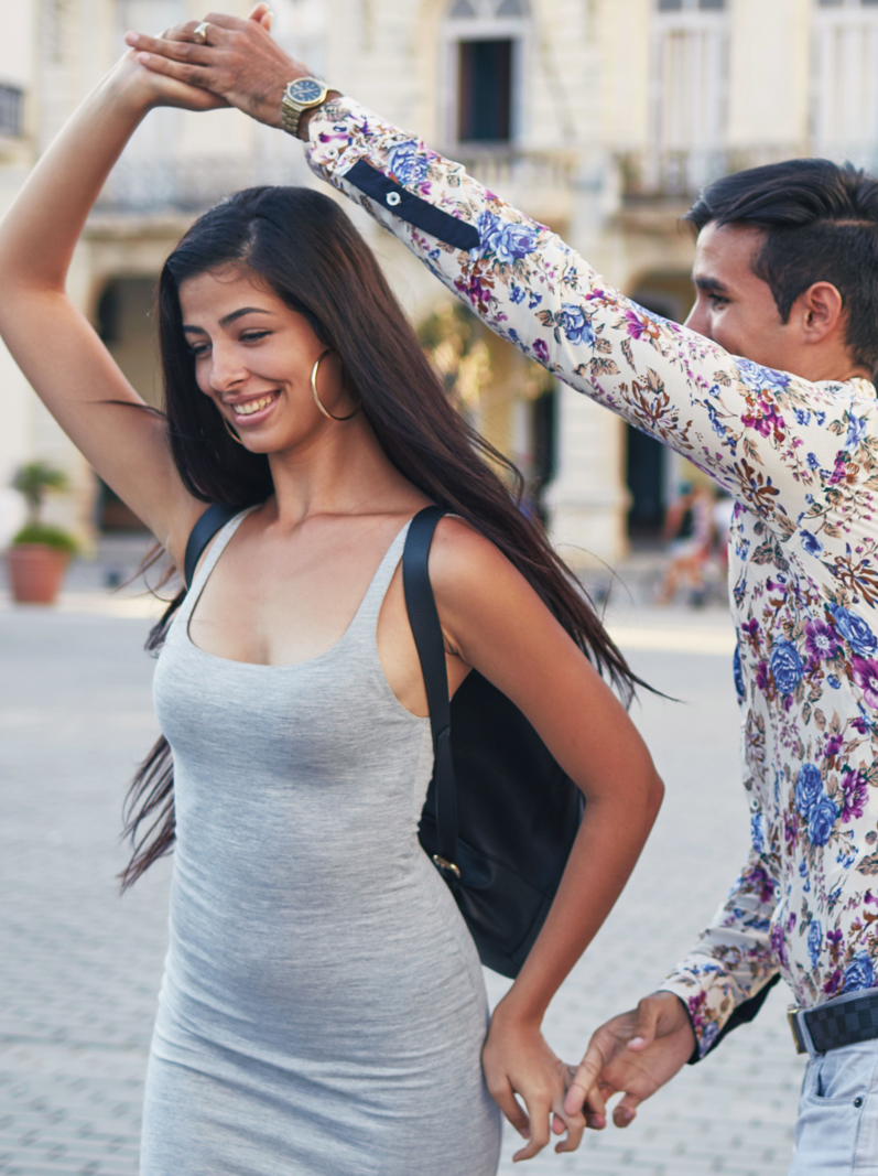 Cropped image of woman photographing friends dancing on town square. Young man and women are enjoying in city. They are wearing casuals.